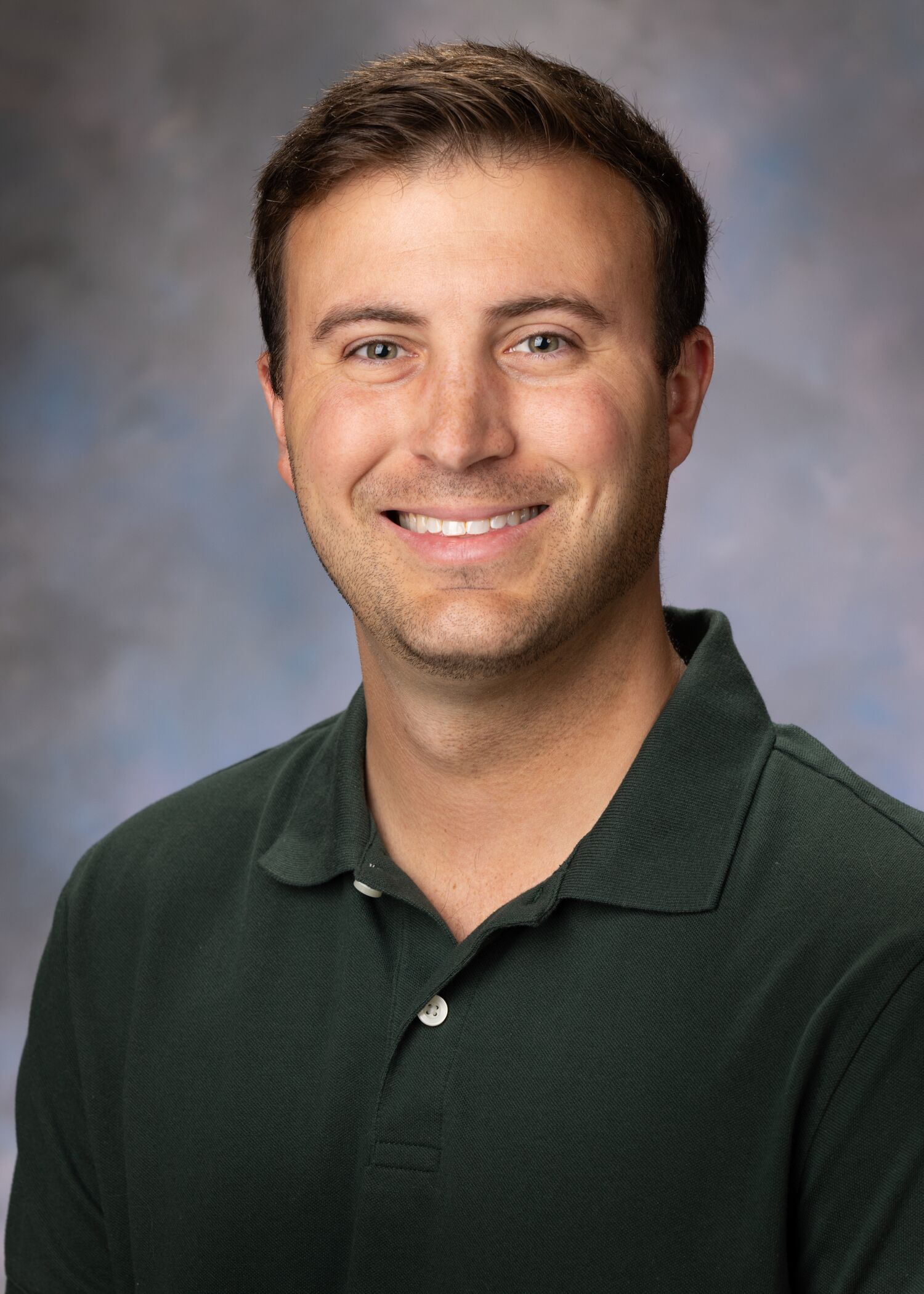 Portrait of Seth Huffman. Seth has short brown hair and is wearing a dark colored polo shirt. 