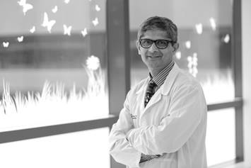 Dr. Sudarshan Jadcherla of Nationwide Children's Hospital posing with arms crossed by a window.