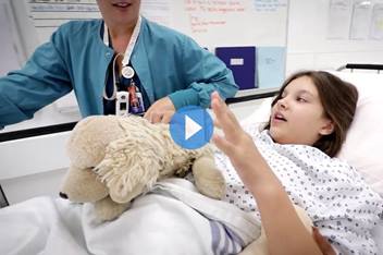 CCPR patient, Christin, in the hospital holding her puppy stuffed animal while been wheeled in on a hospital gurney.