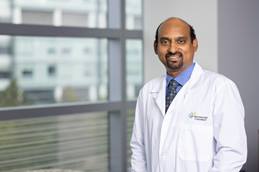Dr. Appakalai is shown wearing a white coat, standing near a window at Nationwide Children's