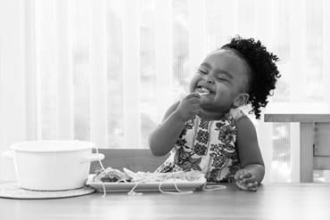 young girl eating pasta