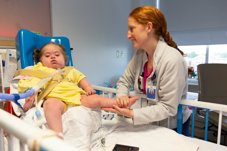 A medical professional providing bedside care to a little girl in a hospital bed.
