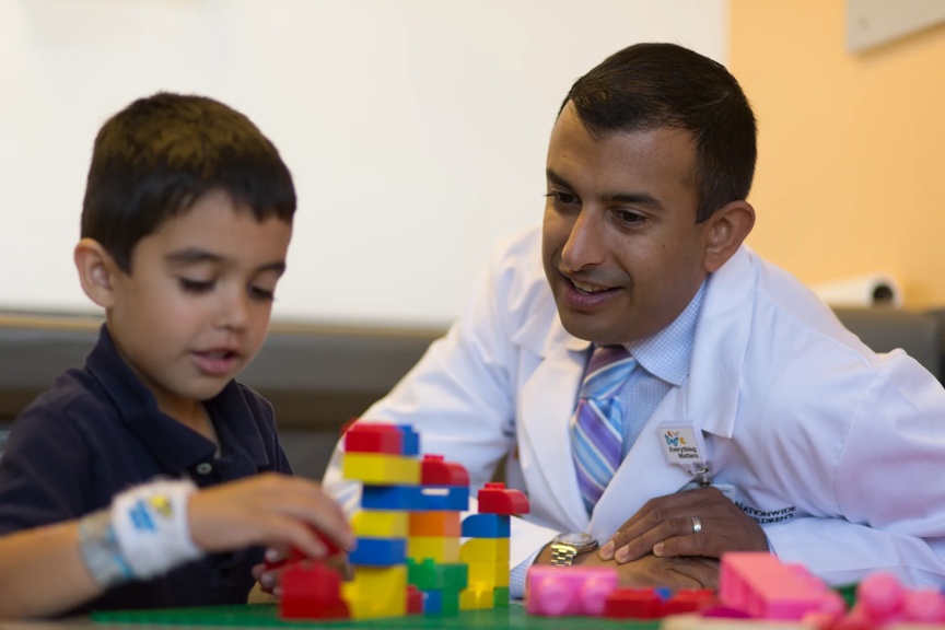 Provider sitting with a young boy while he plays with blocks.