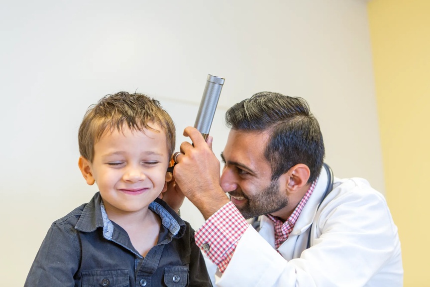 Little boy getting his ear looked at by a medical professional.