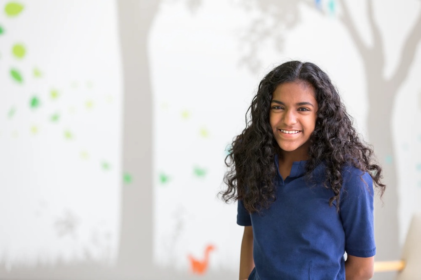 Girl smiling while sitting in the hospital hallway.