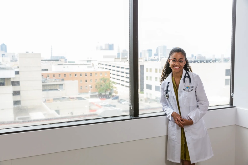 Provider standing by a large window smiling.