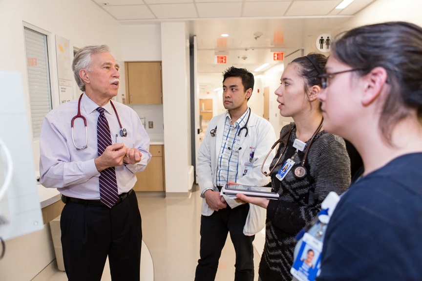 Provider instructing other providers in a hospital hallway.