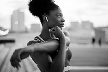 Adolescent girl outside stretching her arms before a run.