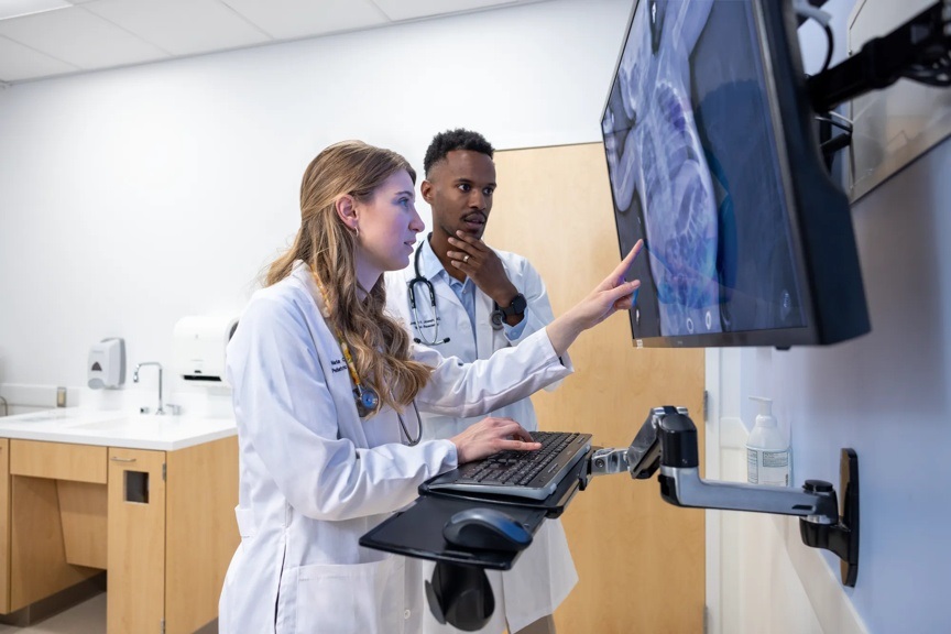 Residents Maria Pepper and Jonathan Joseph are looking at an x-ray of the chest and stomach of a child on a monitor.