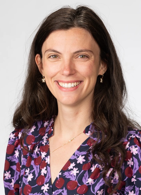 Portrait of Anne Mason, woman with long brown hair and a floral patterned shirt.