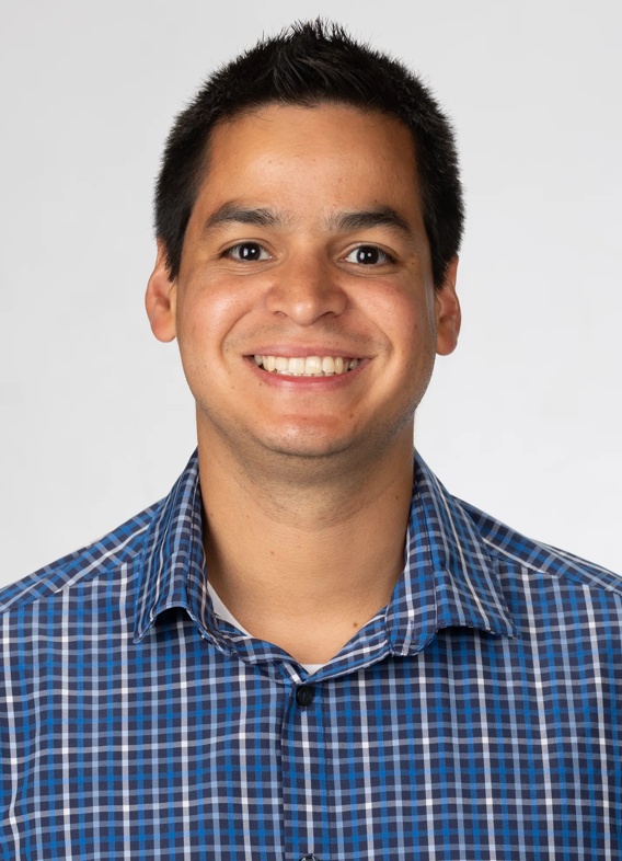 Portrait of Carlos Arias Bermudez, man with short black hair and a striped blue shirt.