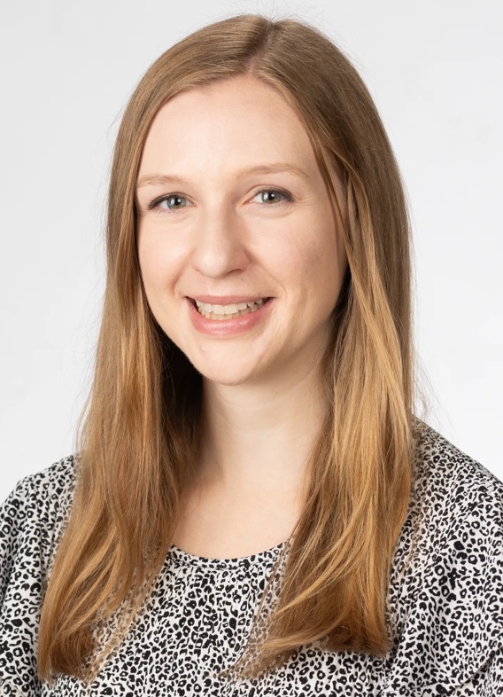 Portrait of Claire Ruz, woman with long blonde hair and a grey shirt.