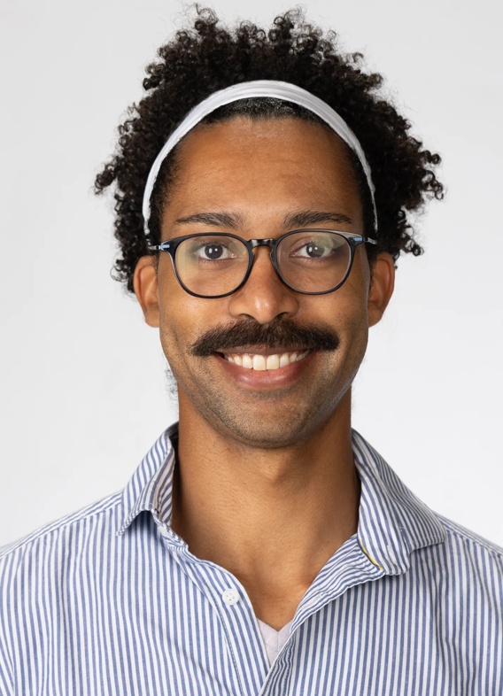 Portrait of Darius Rowe, man with short black hair, glasses, and a light blue shirt.