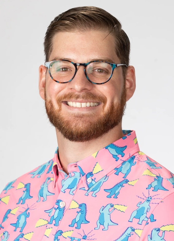 Portrait of Holden Elkhammas, man with short brown hair, glasses, and a patterned pink shirt