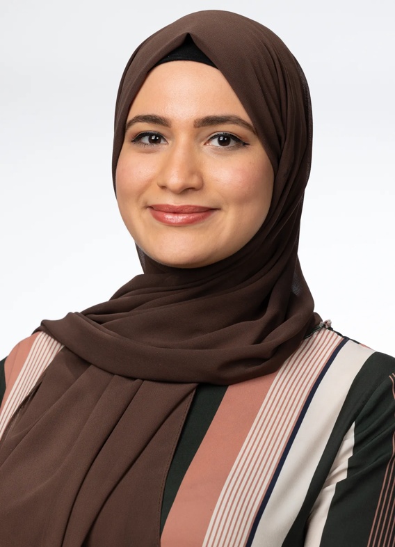 Portrait of May Alarmanazi, woman with a brown head scarf and a striped shirt.