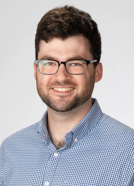 Portrait of Steven Dick, man with short brown hair, glasses, and a blue shirt.