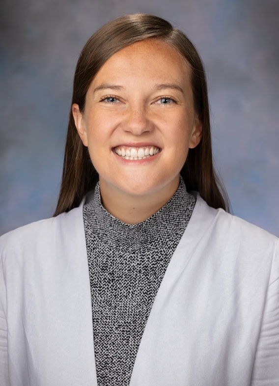 Portrait of Laura Roberts, woman with long brown hair and a white and grey shirt.