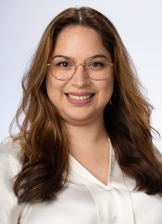 Portrait of Domenica Drouet, woman with long brown hair, glasses, and a white shirt.