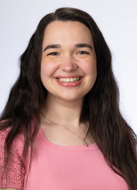 Portrait of Kaitlyn Alleman, woman with long brown hair and a pink shirt.