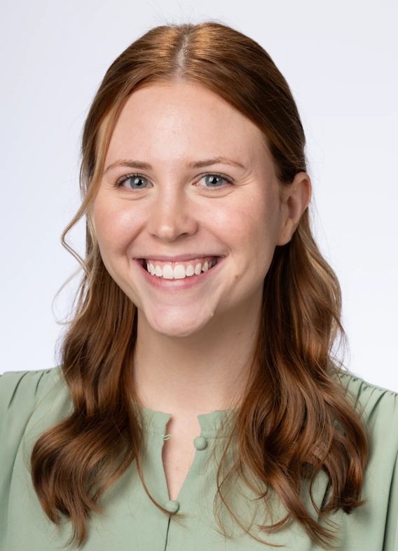 Portrait of Madison Dallas, woman with long red hair and a green shirt.