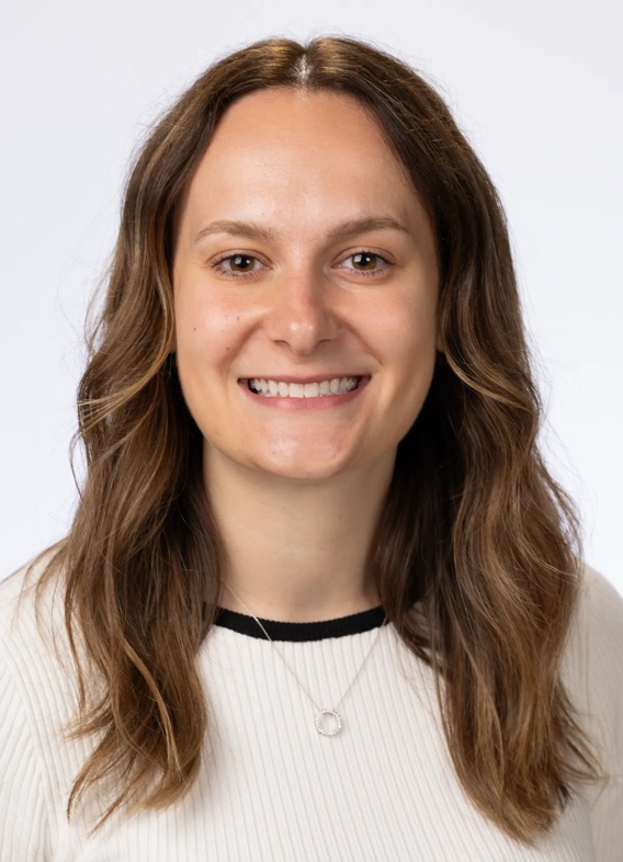 Portrait of Mikhaila Layshock, woman with long brown hair and a white shirt.