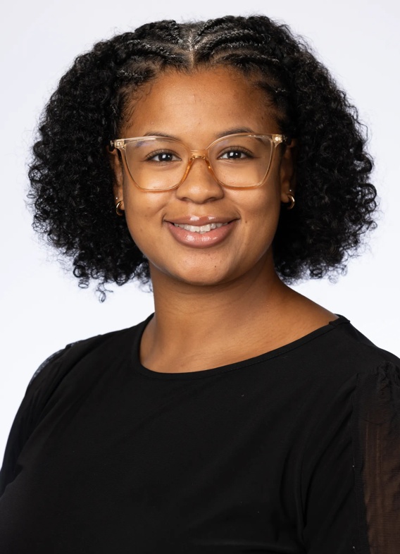 Portrait of Paris Shaw, woman with short black hair, glasses, and a black shirt.