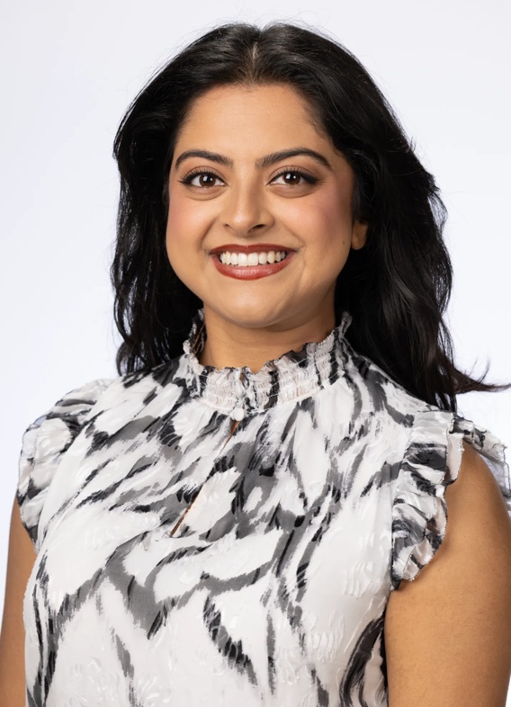 Portrait of Punya Ramesh, woman with long brown hair and a patterned white shirt.