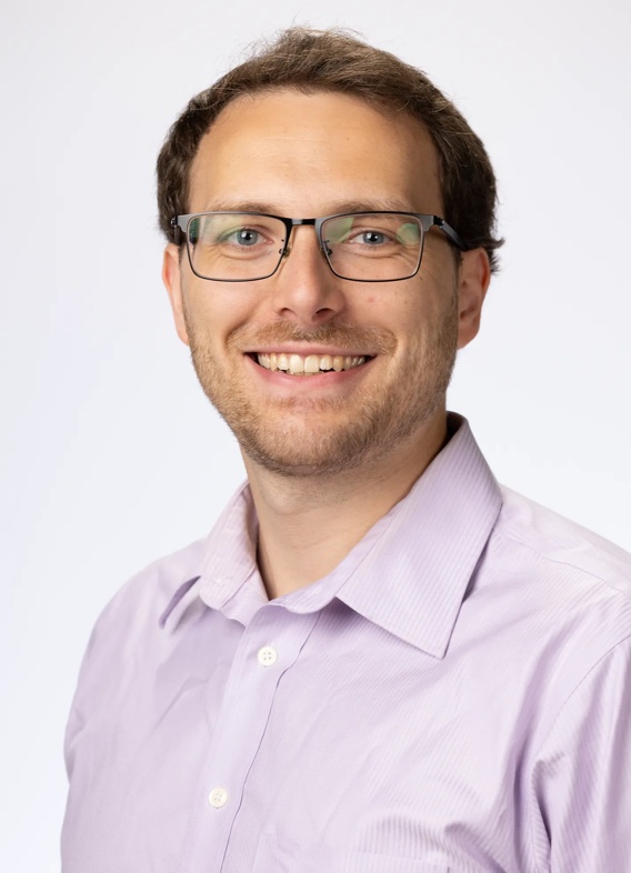 Portrait of Robert Smith Jr, man with short brown hair, glasses, and a light pink shirt.
