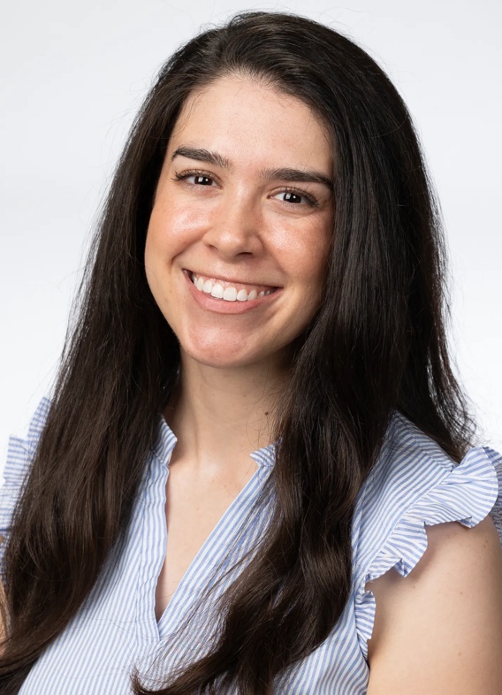 Portrait of Abby Blumenfeld, woman with long brown hair and a light blue shirt.
