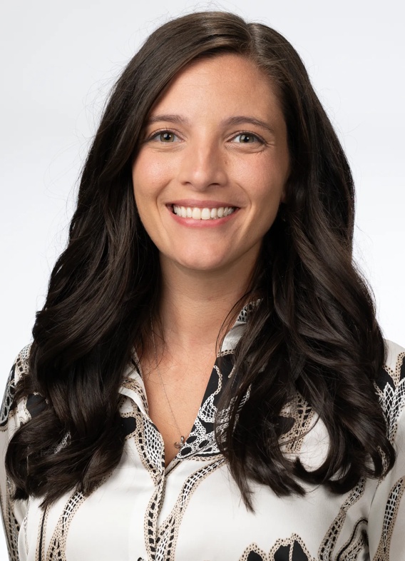 Portrait of Abby Dryden, woman with long brown hair and a white shirt.