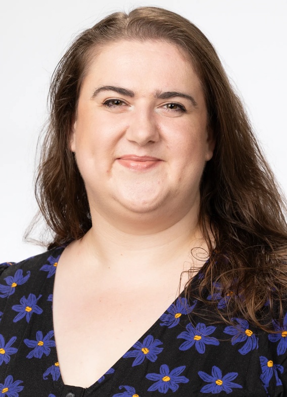 Portrait of Alexandra Worth, woman with long brown hair and a floral shirt.