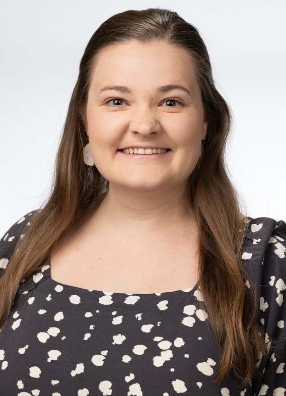 Portrait of Amelia Hill, woman with long brown hair and a patterned brown shirt