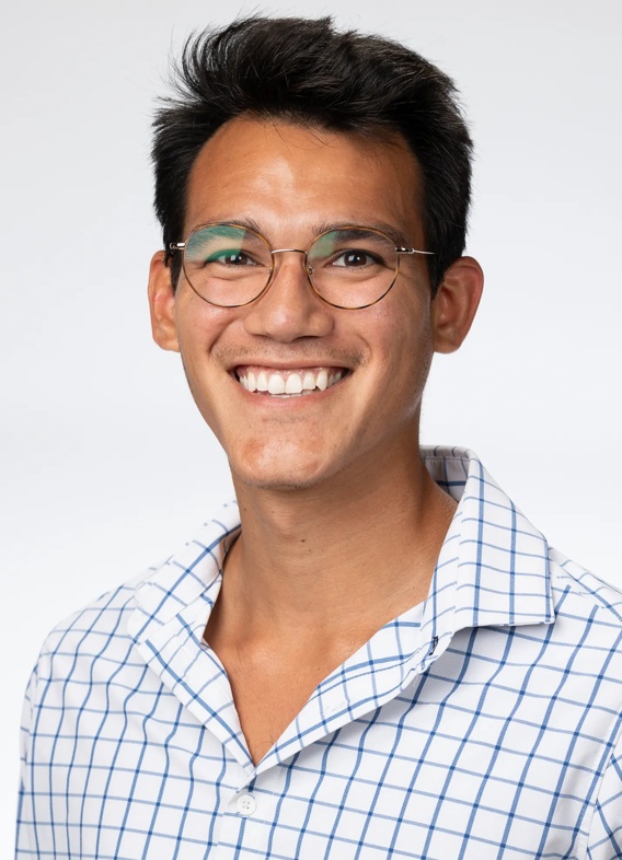 Portrait of Camilo Suescum, man with short black hair, glasses, and a striped white and blue shirt.