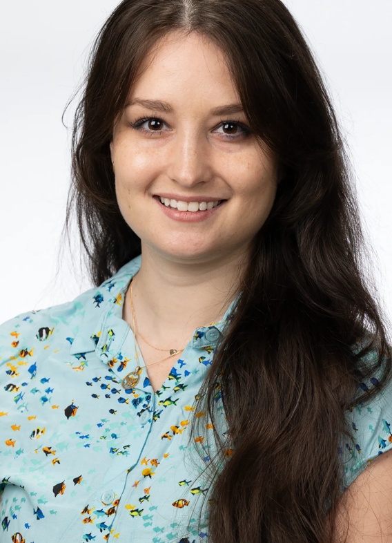 Portrait of Hannah Meghan Kluger, woman with long brown hair and a patterned blue shirt.