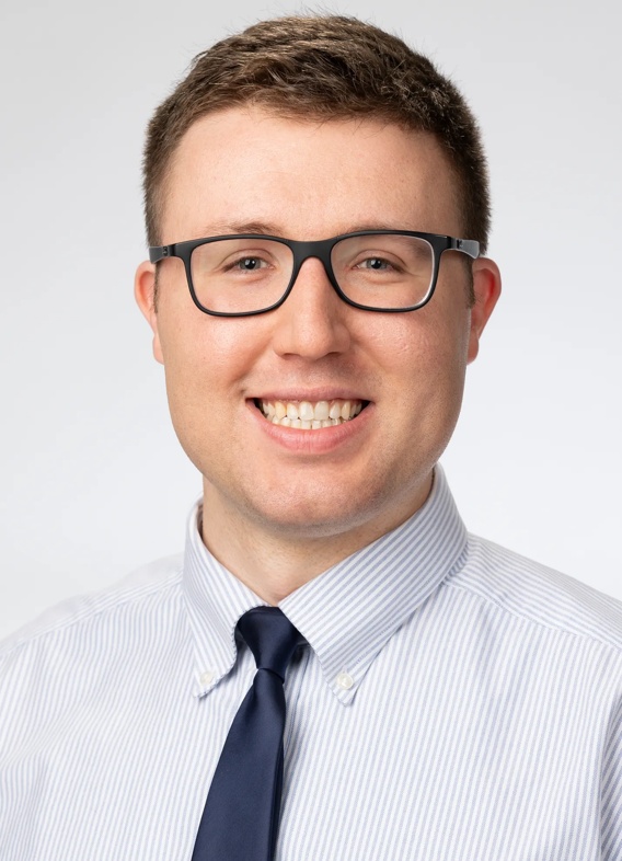 Portrait of Jackson Mittlesteadt, man with short brown hair, glasses, and a white shirt and a tie.
