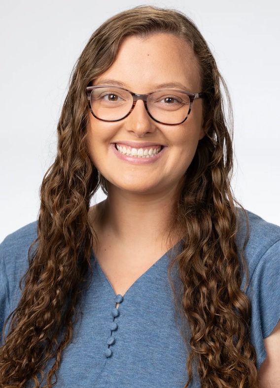 Portrait of Kaitlyn Stevens, woman with long brown hair and a blue shirt.