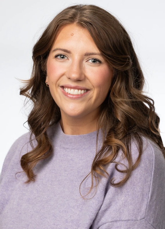 Portrait of Kelsey Fulton, woman with long brown hair and a purple shirt.