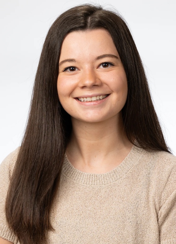 Portrait of Laura Olivieri, woman with long brown hair and a light brown shirt.