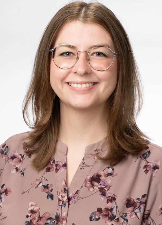 Portrait of Lorna Fletcher, woman with short brown hair, glasses, and a patterned pink shirt.