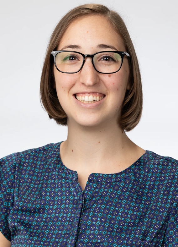 Portrait of Madison Hoenle, woman with short brown hair, glasses, and a blue shirt.