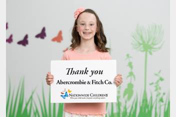 Young girl holding a sign with the Abercrombie and Fitch Co. logo on it.