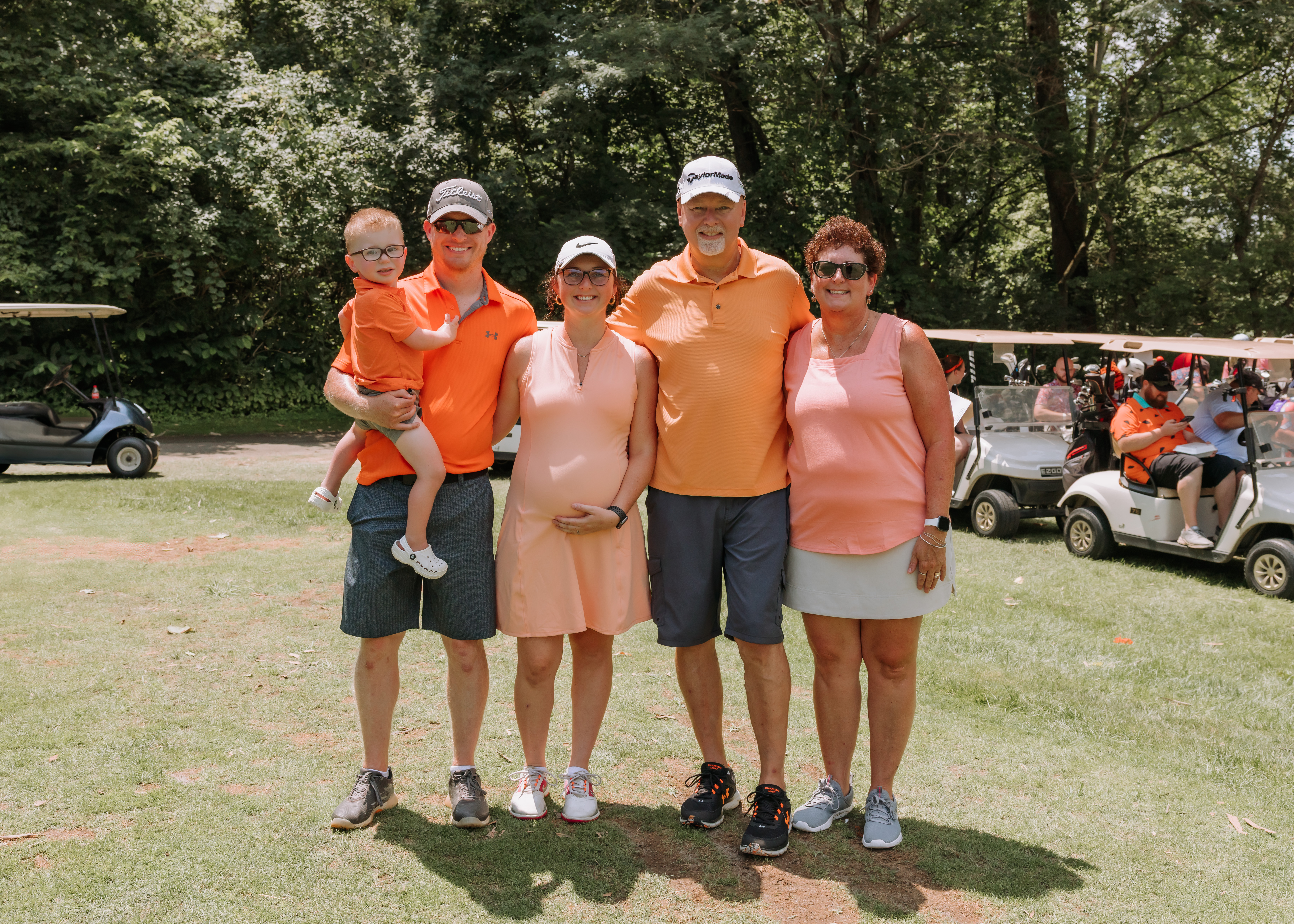 Lu's family and friends smiling at the camera together with golf carts in the background.