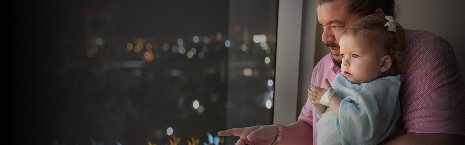 Sweet Georgia looks out the window in awe. She's resting in her dad's arms, wearing a blue hospital gown.
