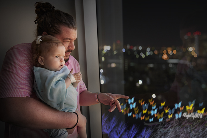 baby girl in dad's arms overlooking hospital lawn at night