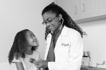 Dr. Delerme and listening to patient's heart in exam room