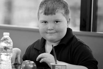 Young Boy Sitting in cafeteria with water bottle and apple