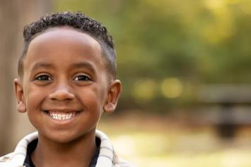 Child sitting outside of Nationwide Children's Hospital, smiling for the camera.
