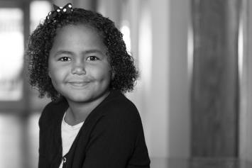 Young Girl Smiling in Light Filled Hallway