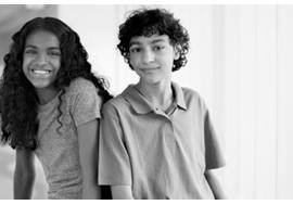 Smiling Tween Girl and Boy Sitting in Hallway