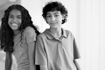 Smiling Tween Girl and Boy Sitting in Hallway